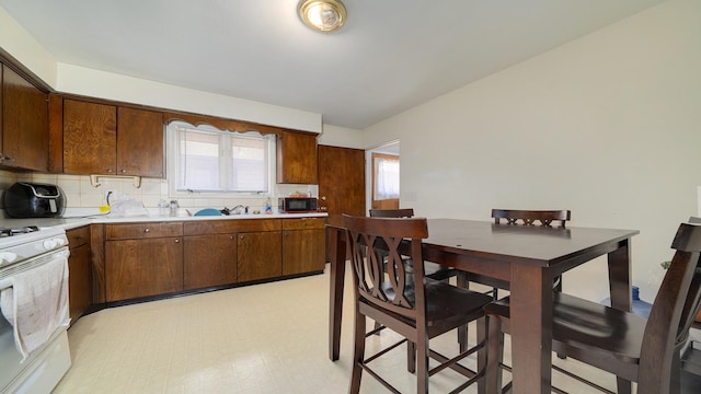 kitchen featuring light countertops, light floors, plenty of natural light, and white range with gas cooktop