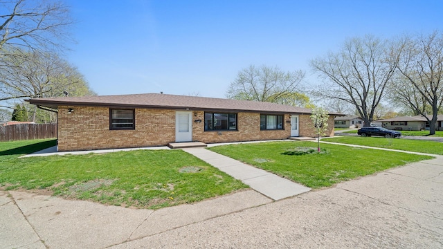 view of front of property featuring brick siding, fence, a shingled roof, and a front lawn