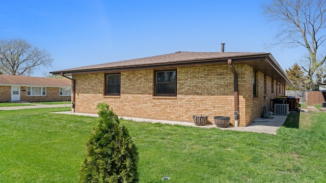view of side of home featuring a lawn, central AC, and brick siding