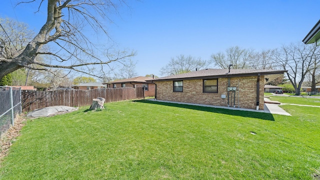 rear view of house featuring brick siding, roof with shingles, fence, and a yard