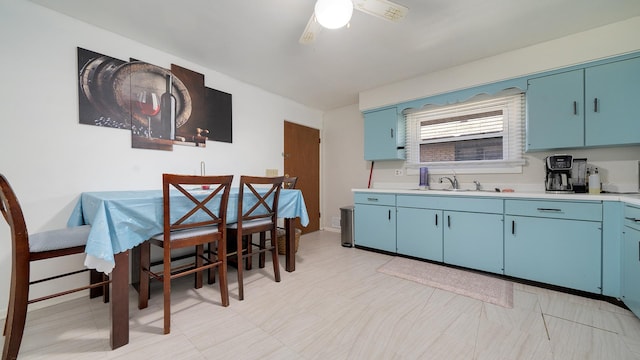 kitchen featuring light countertops, a sink, ceiling fan, and blue cabinetry