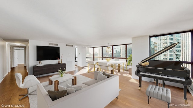 living area featuring baseboard heating, visible vents, floor to ceiling windows, and wood finished floors