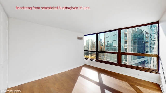 empty room with baseboards, plenty of natural light, wood finished floors, and visible vents