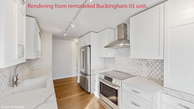 kitchen featuring wall chimney range hood, a sink, stainless steel appliances, white cabinetry, and backsplash
