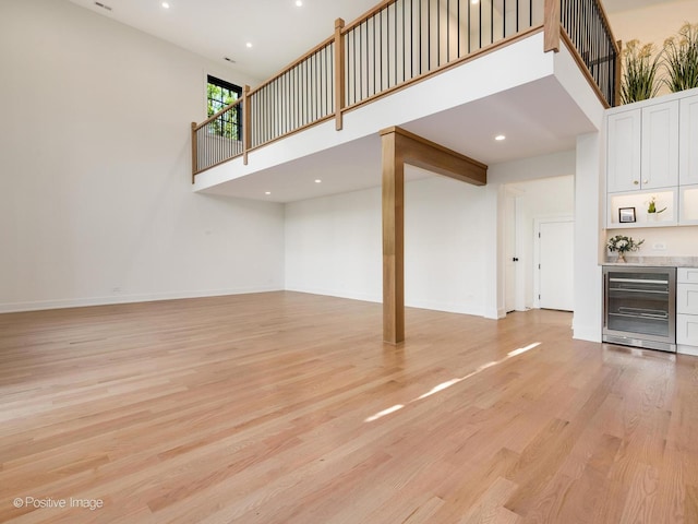 118 Lockerbie Ln, Wilmette, IL 60091 - unfurnished living room featuring beverage cooler, a towering ceiling, a dry bar, light wood-type flooring, and baseboards