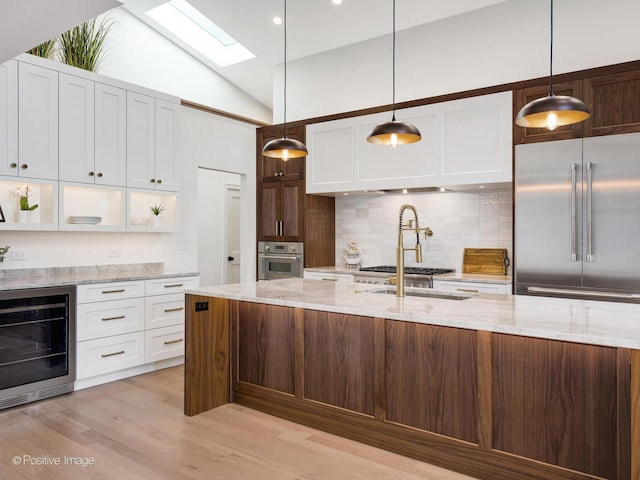 118 Lockerbie Ln, Wilmette, IL 60091 - kitchen featuring stainless steel appliances, beverage cooler, a skylight, white cabinets, and decorative backsplash
