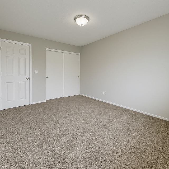 unfurnished bedroom with carpet floors, baseboards, and a closet