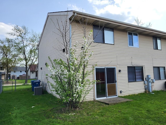 back of property with a lawn, fence, and central air condition unit
