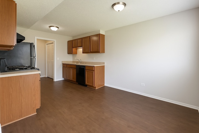 kitchen with light countertops, dark wood finished floors, a sink, and dishwasher
