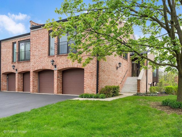 view of front of house with brick siding, a garage, aphalt driveway, and a front yard