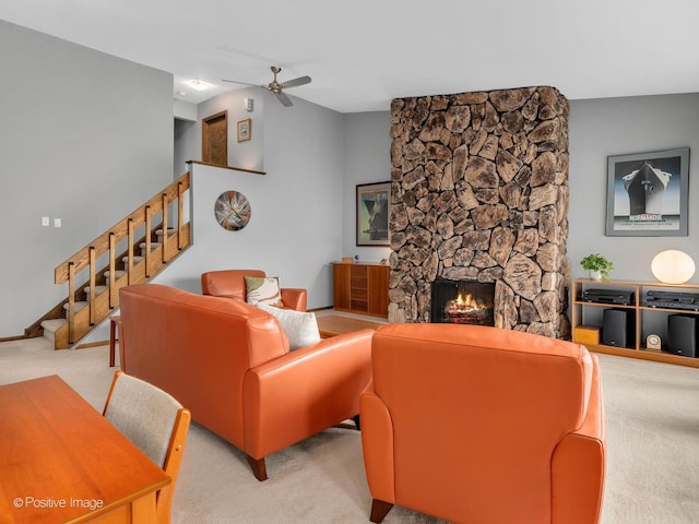 living room featuring a ceiling fan, carpet, a fireplace, and stairway