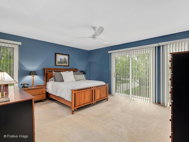 bedroom featuring access to outside, a ceiling fan, light carpet, and multiple windows