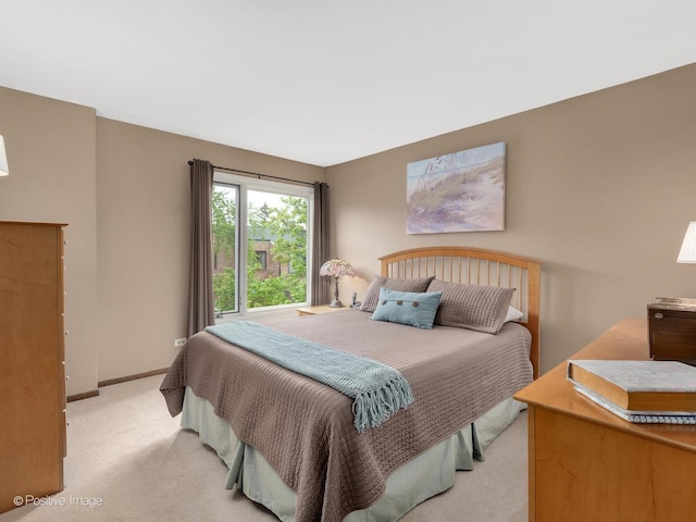 bedroom with light colored carpet and baseboards