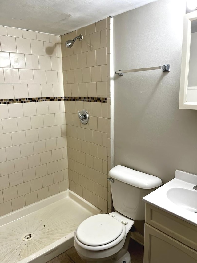 full bathroom with vanity, toilet, and tiled shower