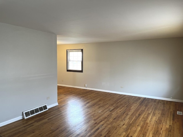 empty room with visible vents, baseboards, and dark wood-style floors