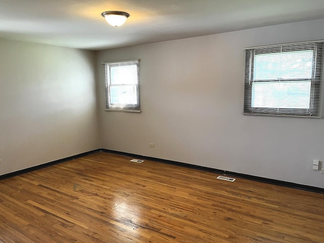 unfurnished room featuring visible vents, baseboards, and wood finished floors