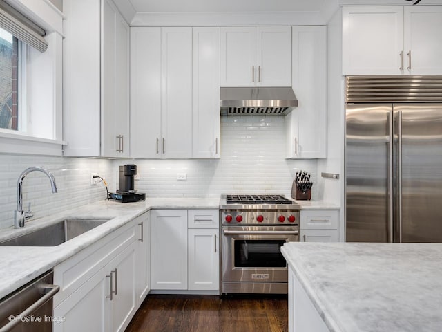 kitchen with high quality appliances, under cabinet range hood, a sink, and white cabinetry