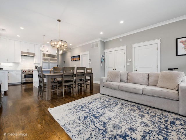 living room featuring a chandelier, dark wood-style floors, ornamental molding, recessed lighting, and baseboards