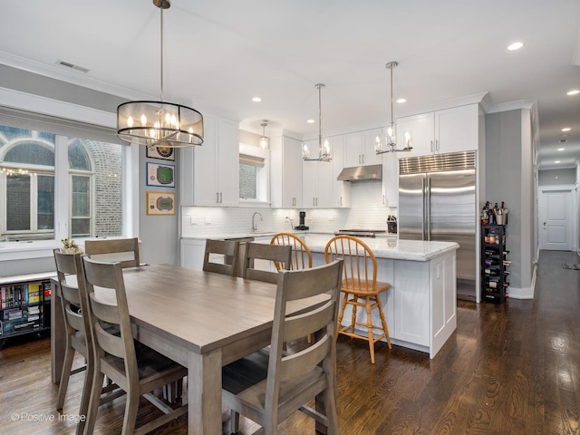 dining area with a chandelier, crown molding, dark wood-type flooring, and recessed lighting