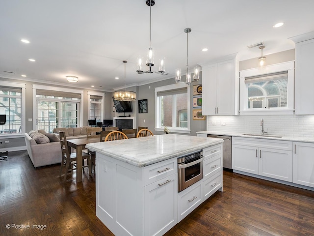 kitchen with a sink, stainless steel appliances, a chandelier, crown molding, and open floor plan