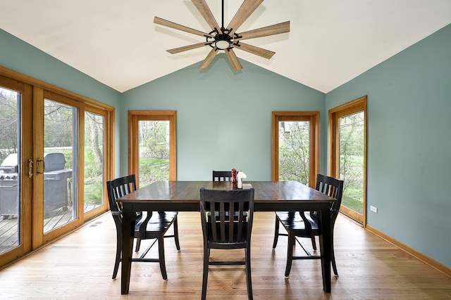 dining room with light wood-style floors, a ceiling fan, a wealth of natural light, and vaulted ceiling