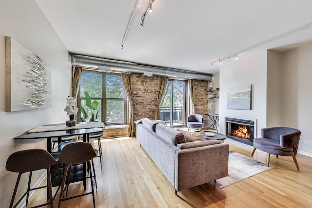 1735 W Diversey Pkwy Unit 206, Chicago, IL 60614 - living area featuring rail lighting, a lit fireplace, light wood-style floors, and brick wall