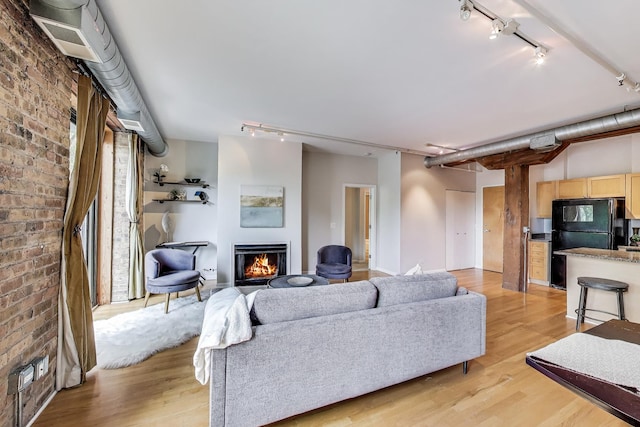 1735 W Diversey Pkwy Unit 206, Chicago, IL 60614 - living area featuring rail lighting, brick wall, a lit fireplace, and light wood-style flooring