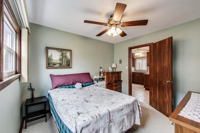 bedroom featuring a ceiling fan, light tile patterned flooring, light carpet, and ensuite bathroom