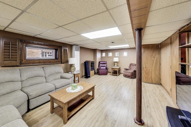 living area with a drop ceiling and light wood-type flooring