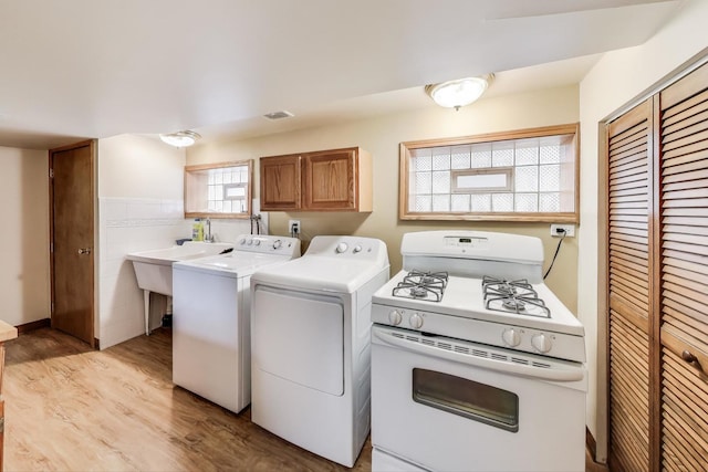 clothes washing area featuring laundry area, wainscoting, light wood-style flooring, and washer and dryer