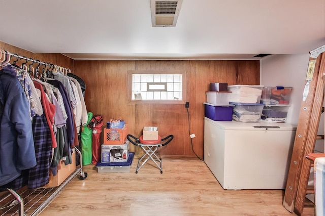 laundry area featuring visible vents, wood walls, and wood finished floors