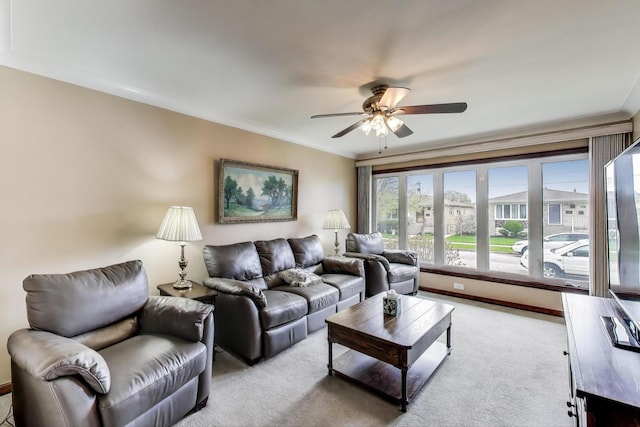 carpeted living room with crown molding, ceiling fan, and baseboards