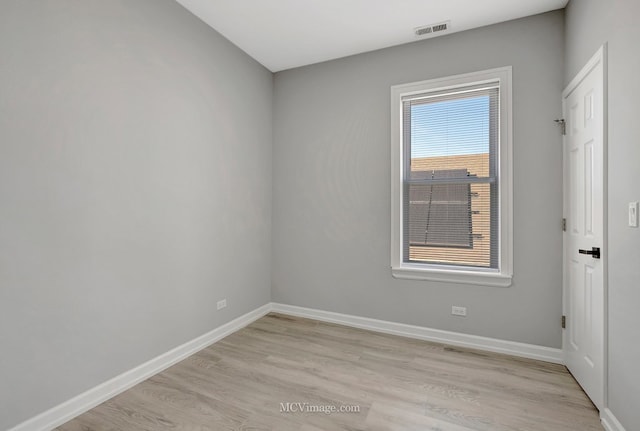 empty room with baseboards, visible vents, and light wood-type flooring