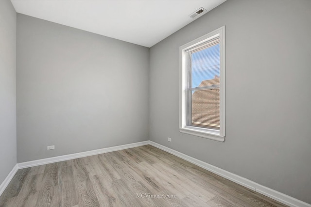 empty room featuring baseboards, visible vents, and wood finished floors