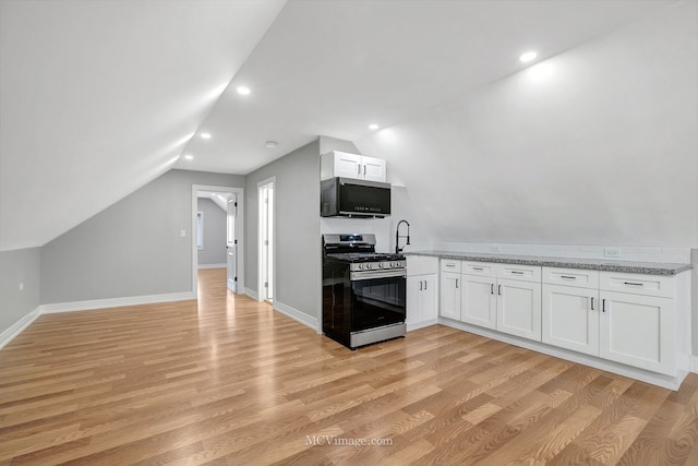 kitchen with white cabinets, black microwave, stainless steel gas range oven, and vaulted ceiling