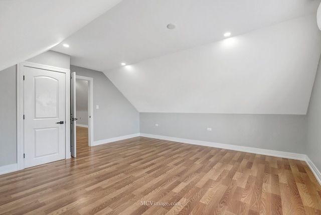additional living space featuring baseboards, light wood finished floors, and lofted ceiling