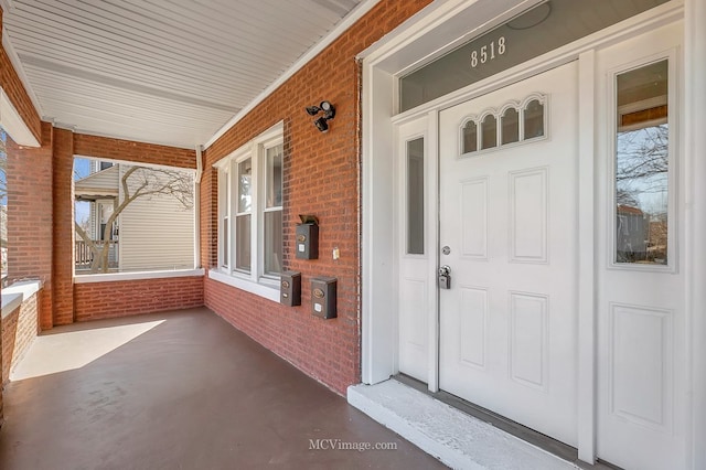 entrance to property with a porch and brick siding