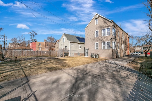 rear view of property with a lawn, fence, and driveway