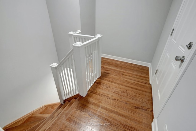 staircase with baseboards and wood finished floors