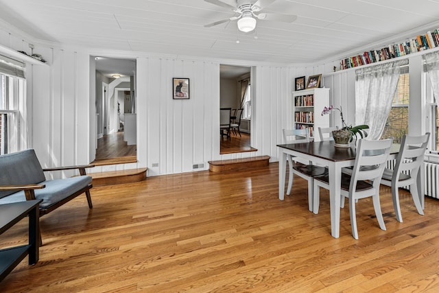 dining area featuring visible vents, ornamental molding, radiator, a ceiling fan, and light wood-style flooring