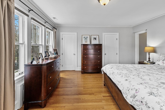 bedroom featuring crown molding, light wood-type flooring, and visible vents
