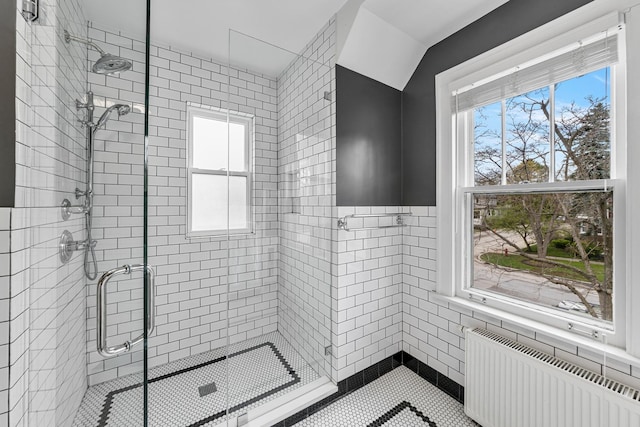 bathroom with a stall shower, radiator heating unit, and tile walls