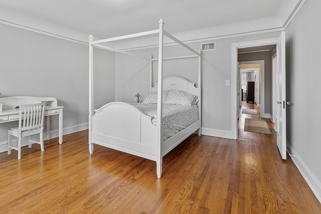 bedroom with visible vents, baseboards, and wood finished floors