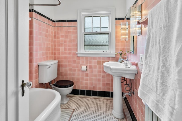 bathroom with a sink, tile walls, toilet, and a bathtub