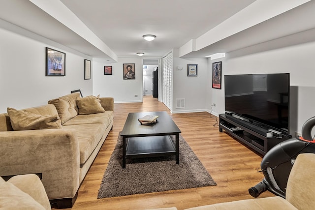 living room featuring light wood-style floors, baseboards, and visible vents