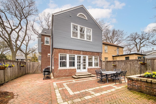 rear view of property featuring french doors, brick siding, a fenced backyard, a patio, and entry steps