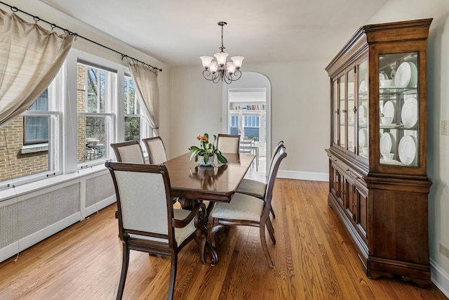dining area with baseboards, light wood finished floors, and a chandelier