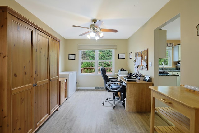 home office with a sink, baseboards, a ceiling fan, and light wood finished floors