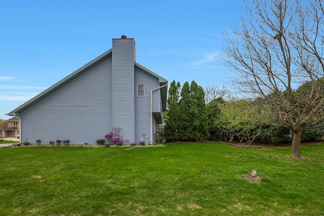view of side of property with a chimney and a yard