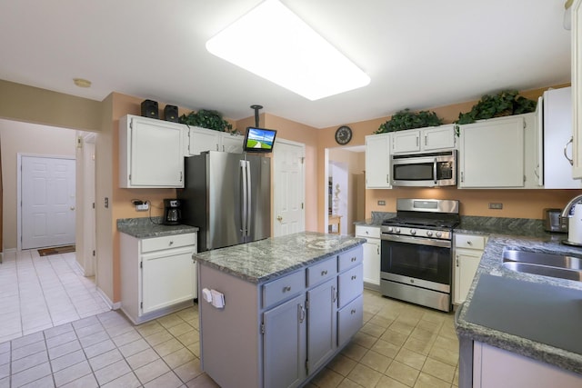 kitchen featuring a kitchen island, light tile patterned flooring, appliances with stainless steel finishes, and a sink